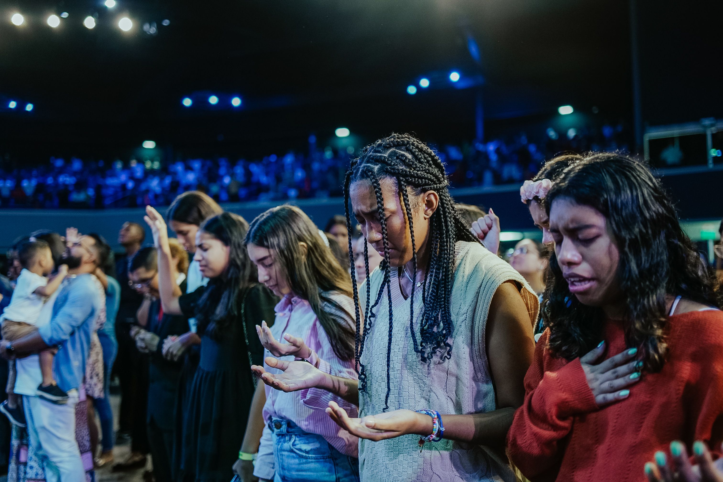 A diverse group of young adults praying together